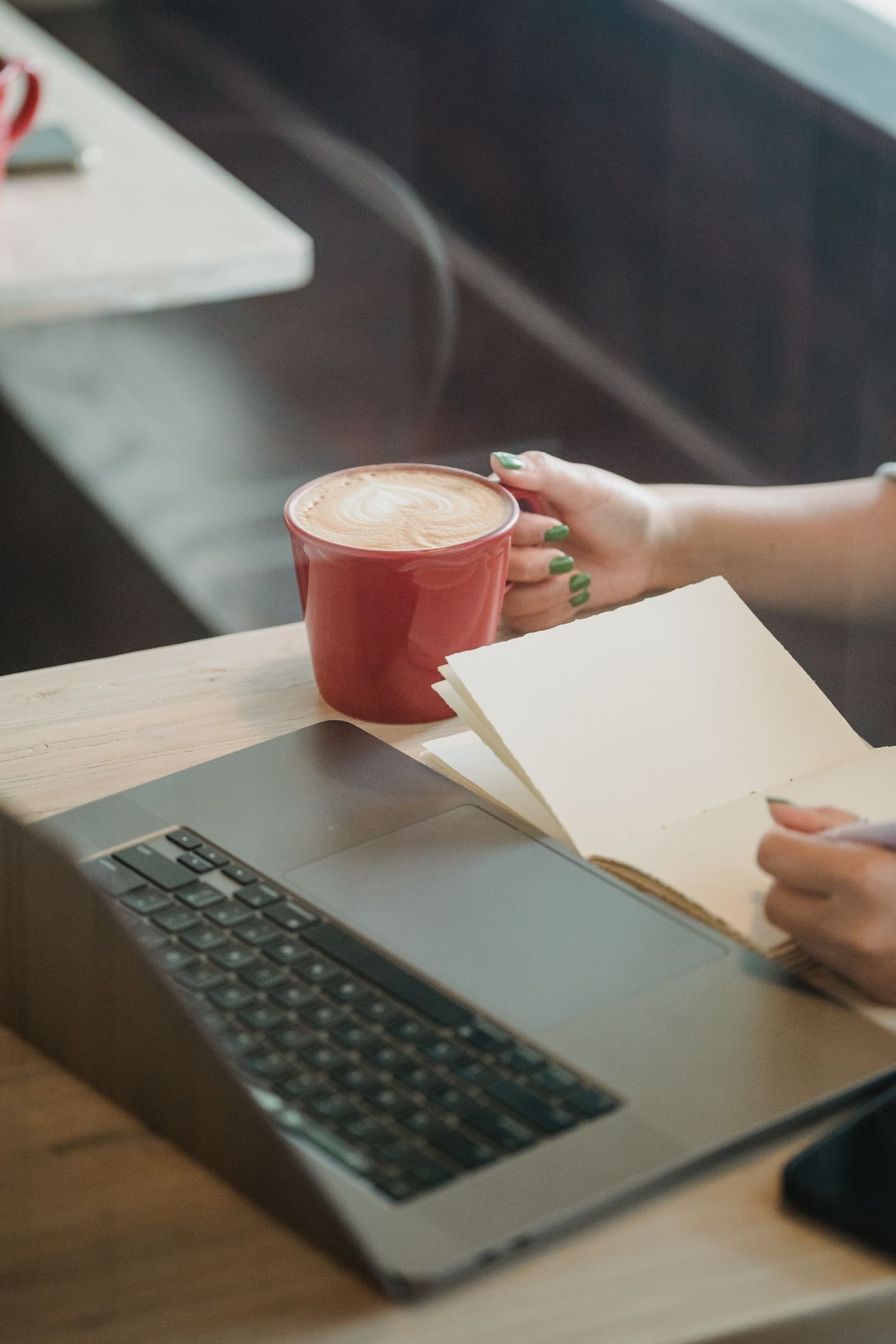 A quiet moment with a laptop, coffee and notebook at a cafe.